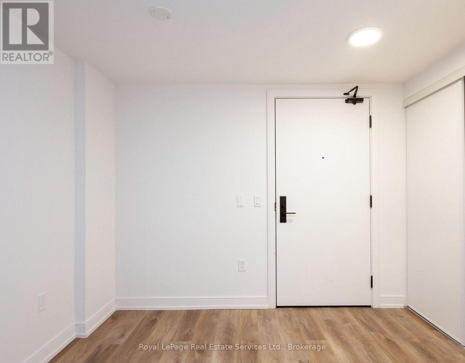 A white door with a black handle is in a room with wooden floors and white walls.