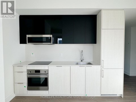 A modern kitchen with white cabinets and a black countertop.
