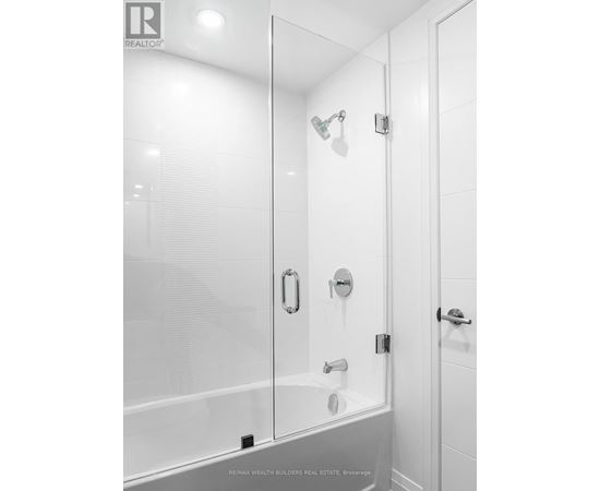 A white bathroom with a glass shower door and a white tub.
