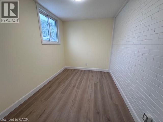 A room with wooden flooring and a white brick wall.