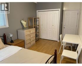 A bedroom with a bed, dresser, and wardrobe.