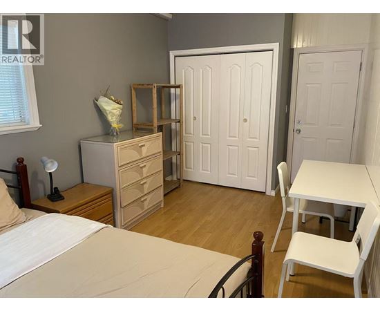 A bedroom with a bed, dresser, and wardrobe.