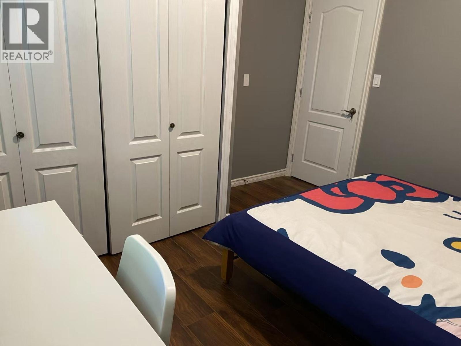 A bedroom with a bed, a table and chairs, and a wardrobe.