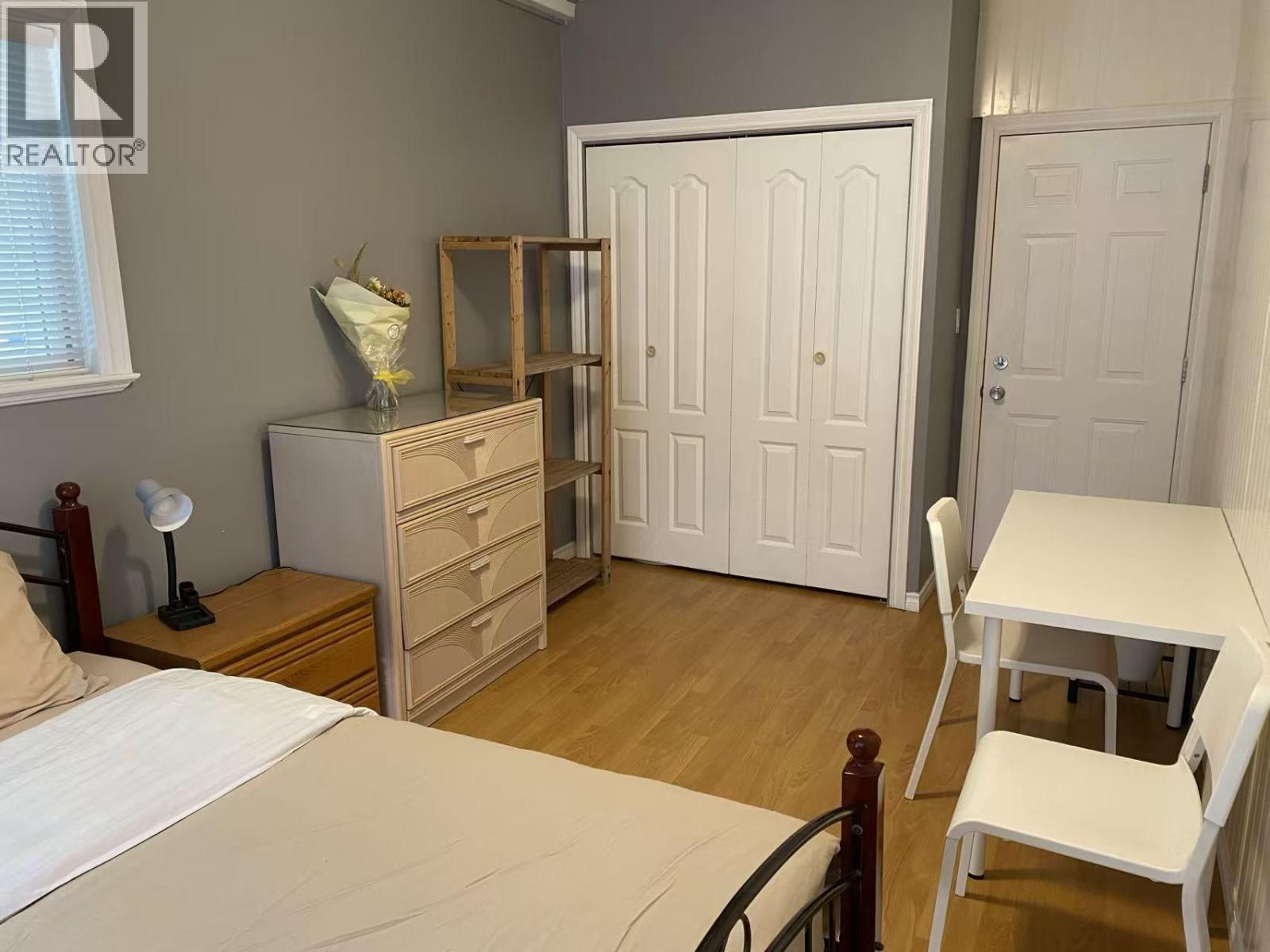 A bedroom with a bed, dresser, and chair.