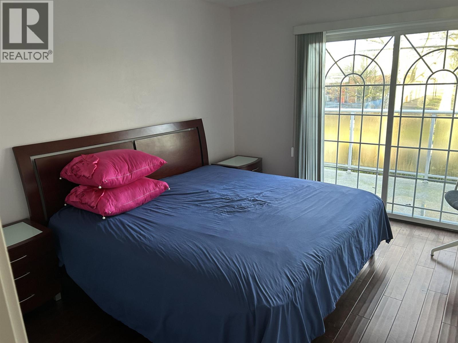 A bed with a blue sheet and two pink pillows.