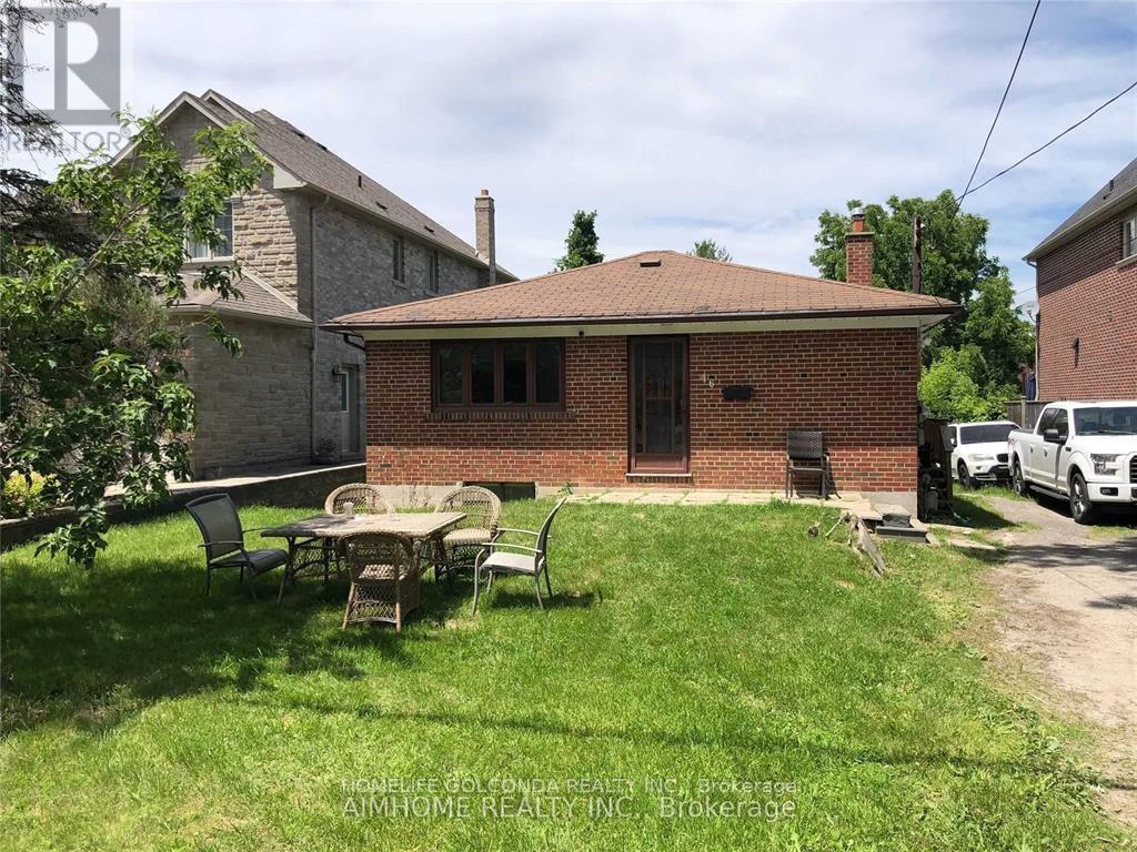 A small brick house with a patio and lawn chairs.