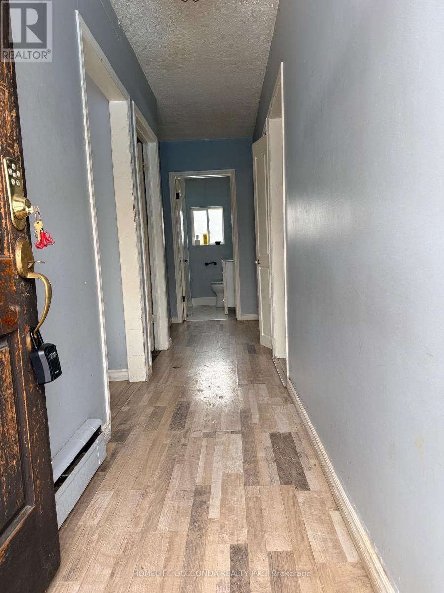 A long, narrow hallway with a wooden floor and white walls.
