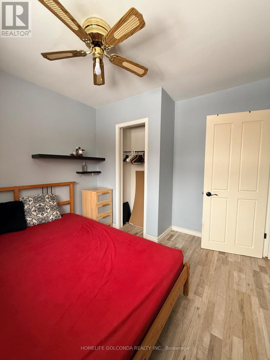 A bedroom with a red bed and a ceiling fan.