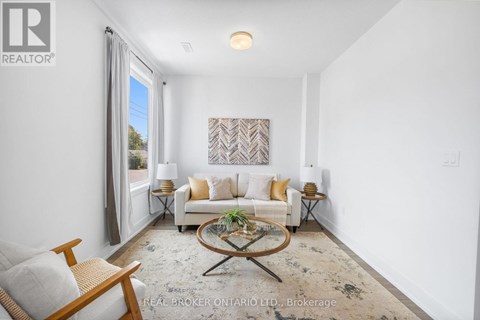 A living room with a white couch, a coffee table, and a painting on the wall.