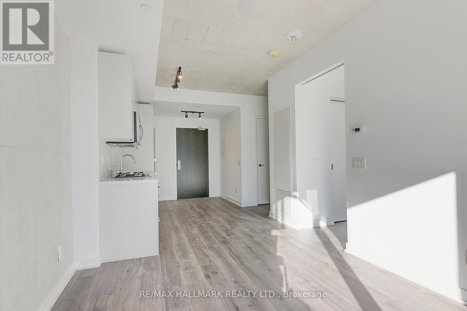 A spacious room with a white ceiling and wooden flooring.