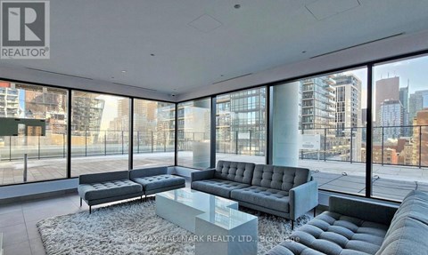 A living room with a grey sofa and a glass table.