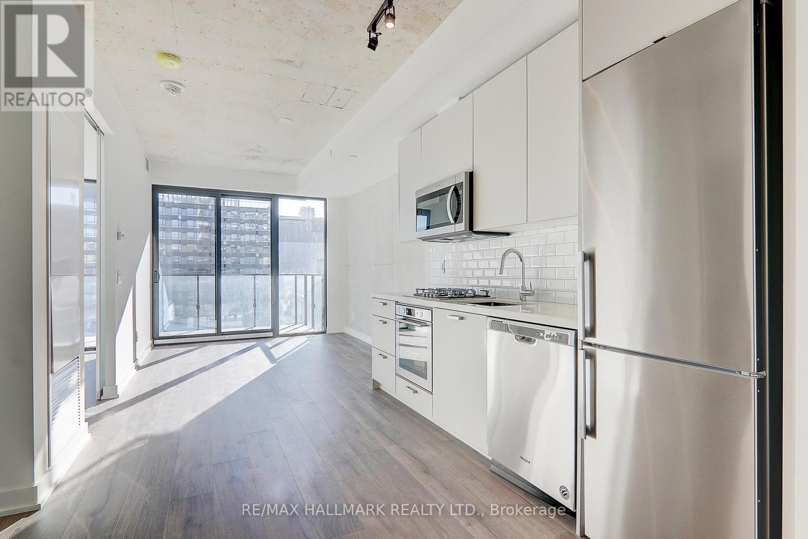 A kitchen with white cabinets and a stainless steel refrigerator.