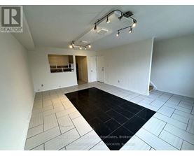 A spacious room with a black rug in the middle and white walls.