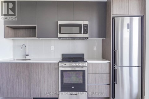 A modern kitchen with a stainless steel refrigerator and a stove top oven.