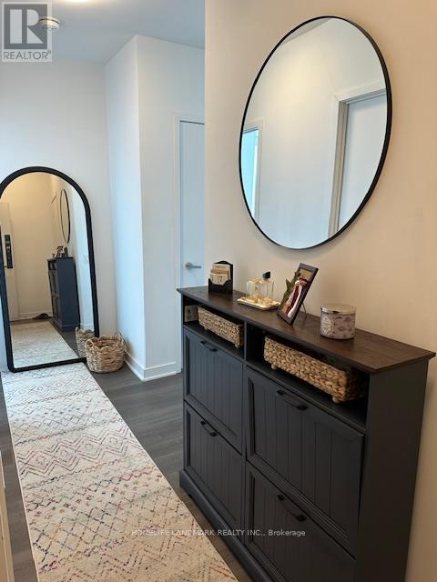 A hallway with a black cabinet and a round mirror on the wall.
