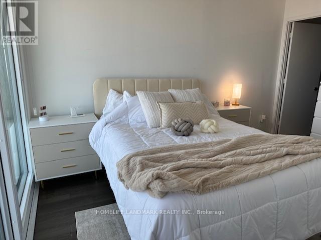 A bedroom with a large bed, a nightstand with a lamp, and a window with curtains.