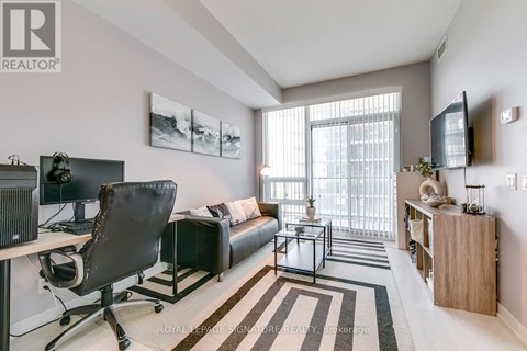 A well-lit, modern living room with a black leather chair and a television.