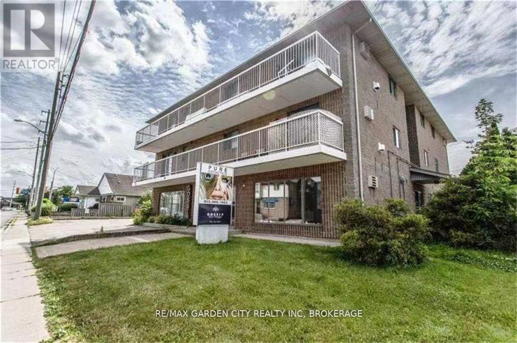 A building with a balcony and a sign that says RE/MAX GARDEN CITY REALTY INC. BROKERAGE.
