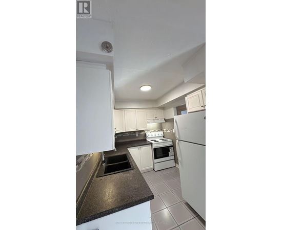 A kitchen with white appliances and a black counter top.