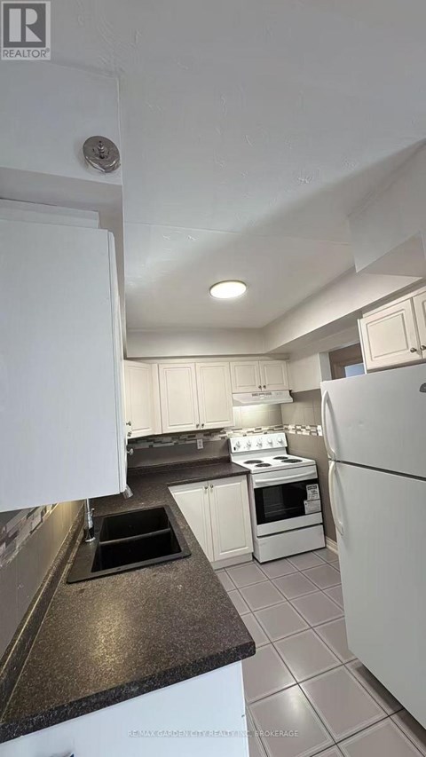 A kitchen with white appliances and a black counter top.
