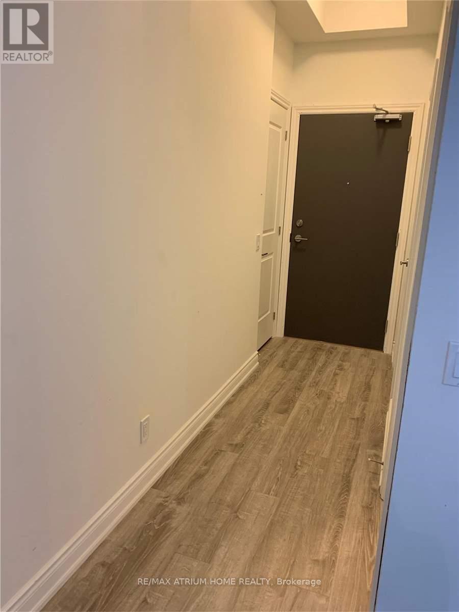 A hallway with a black door and wooden flooring.