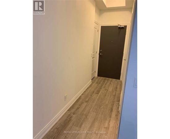 A hallway with a black door and wooden flooring.