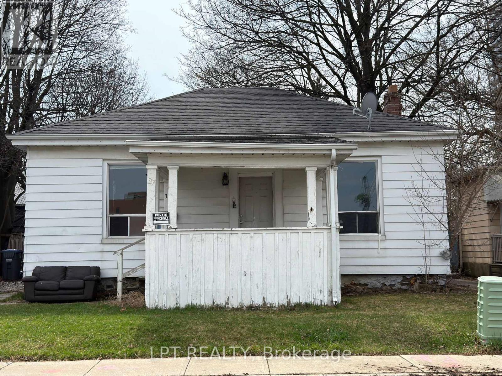 A white house with a black roof and a sign that says I.P.T. Realty Brokerage.