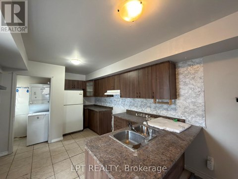 A kitchen with a sink, refrigerator, and cabinets.
