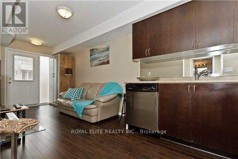 A modern kitchen with dark wood cabinets and a beige couch with a blue throw pillow.