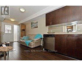 A modern kitchen with dark wood cabinets and a beige couch with a blue throw pillow.