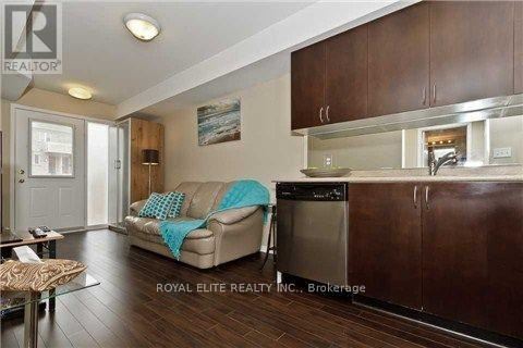 A modern kitchen with dark wood cabinets and a beige couch with a blue throw pillow.