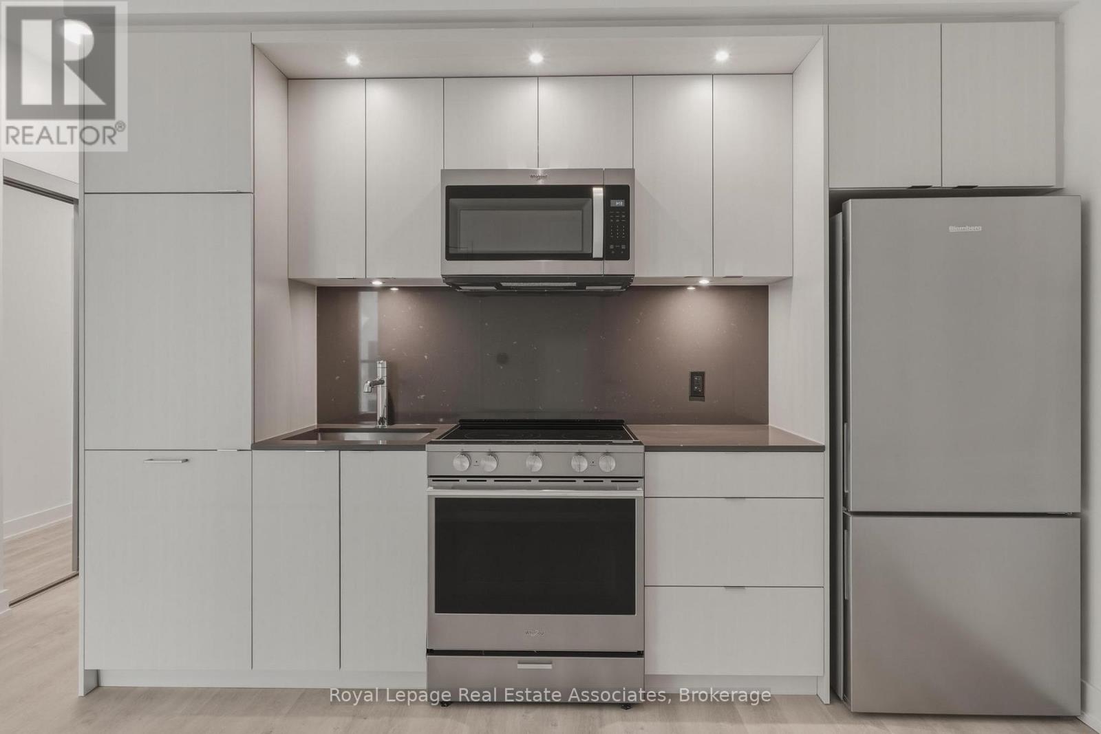 A modern kitchen with white cabinets and stainless steel appliances.