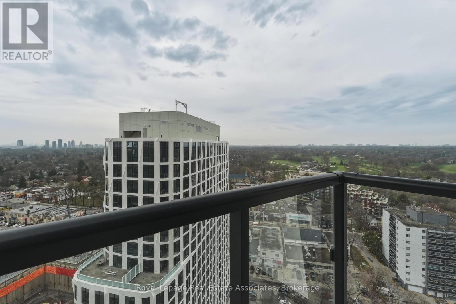 A tall white building with a balcony overlooking a cityscape.