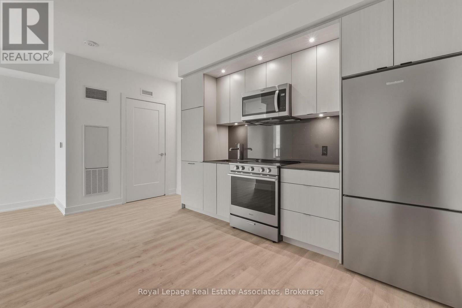 A modern kitchen with stainless steel appliances and wooden flooring.
