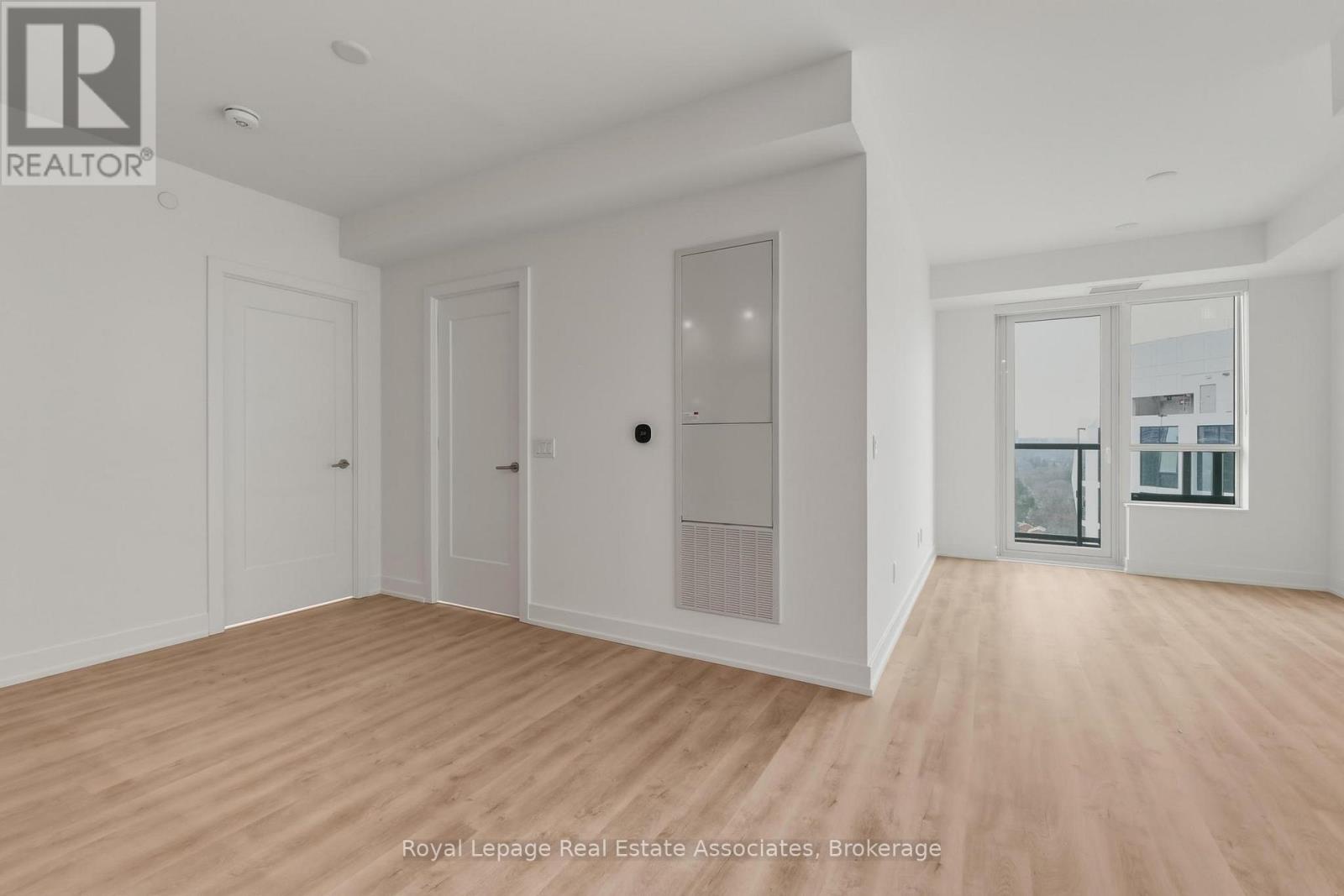 A spacious room with wooden flooring and white walls.