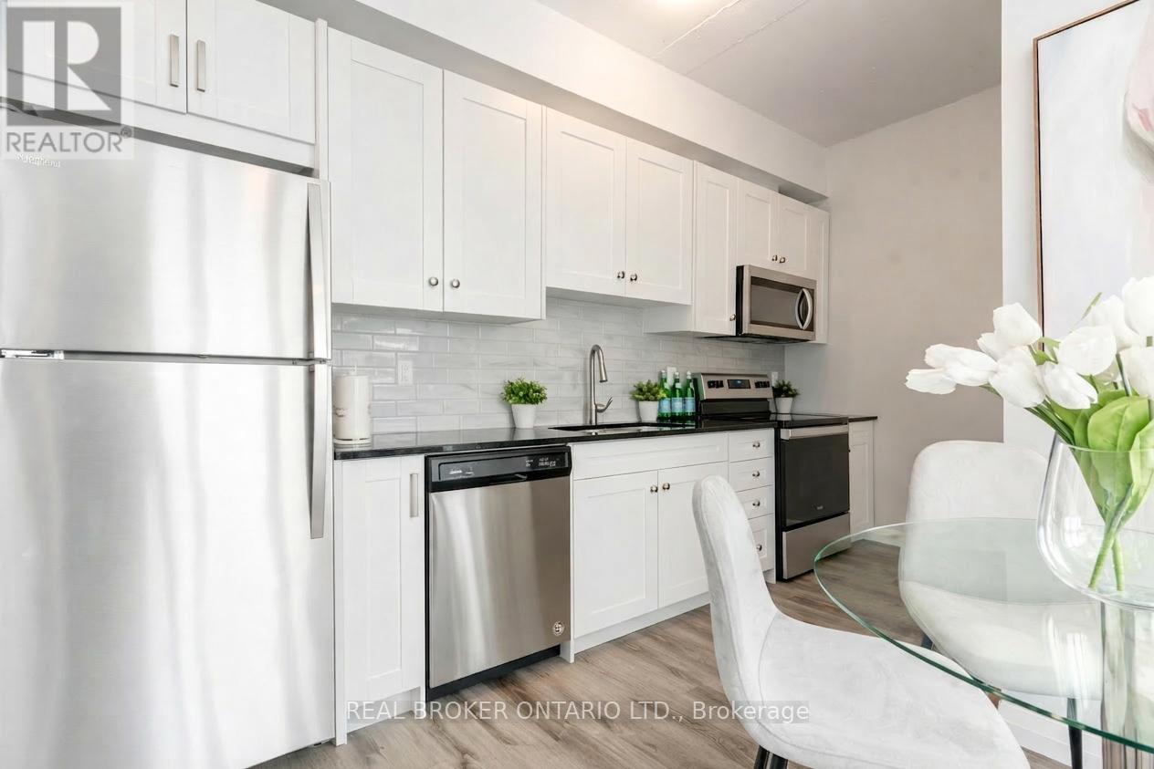 A white kitchen with a glass table and a vase of white flowers.