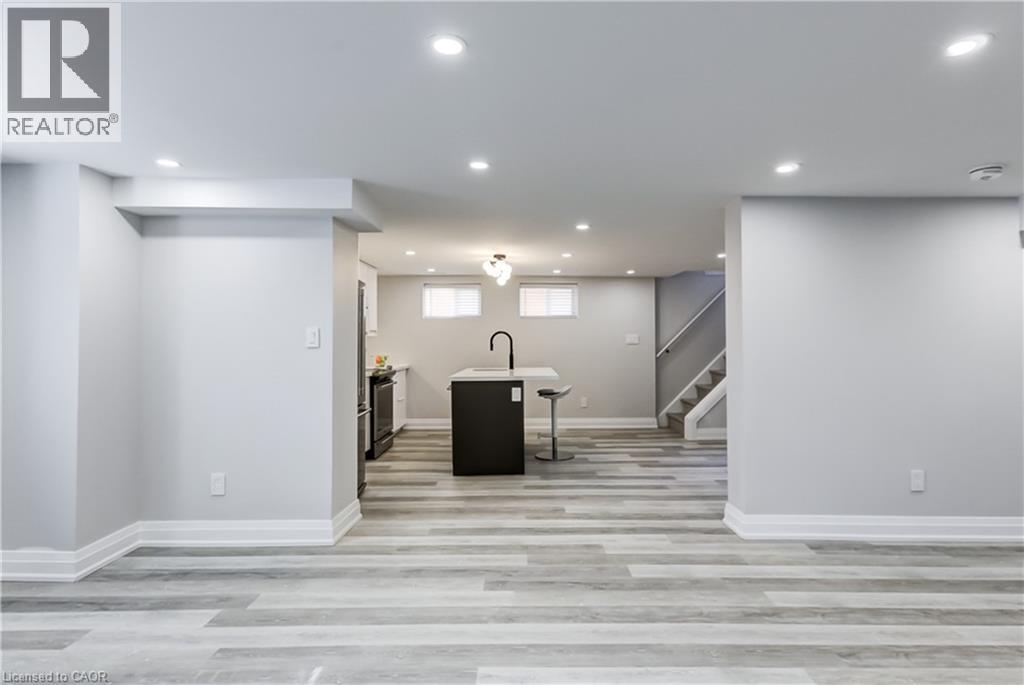 A spacious room with a black sofa and a staircase in the background.