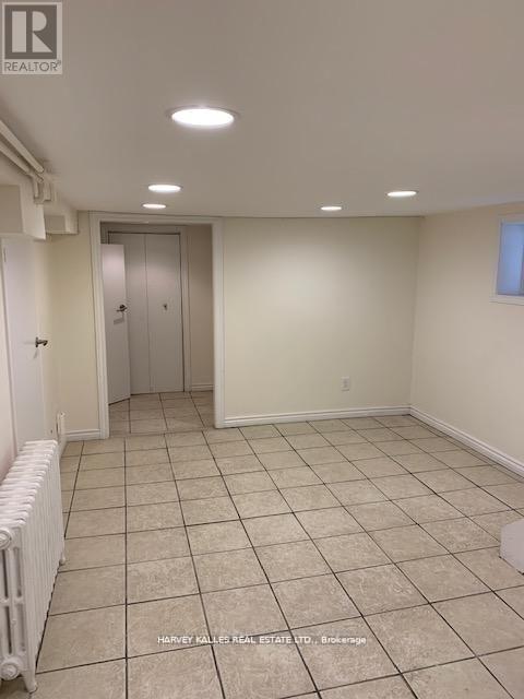 A room with white walls and tile flooring, with a radiator on the left side.