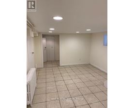 A room with white walls and tile flooring, with a radiator on the left side.