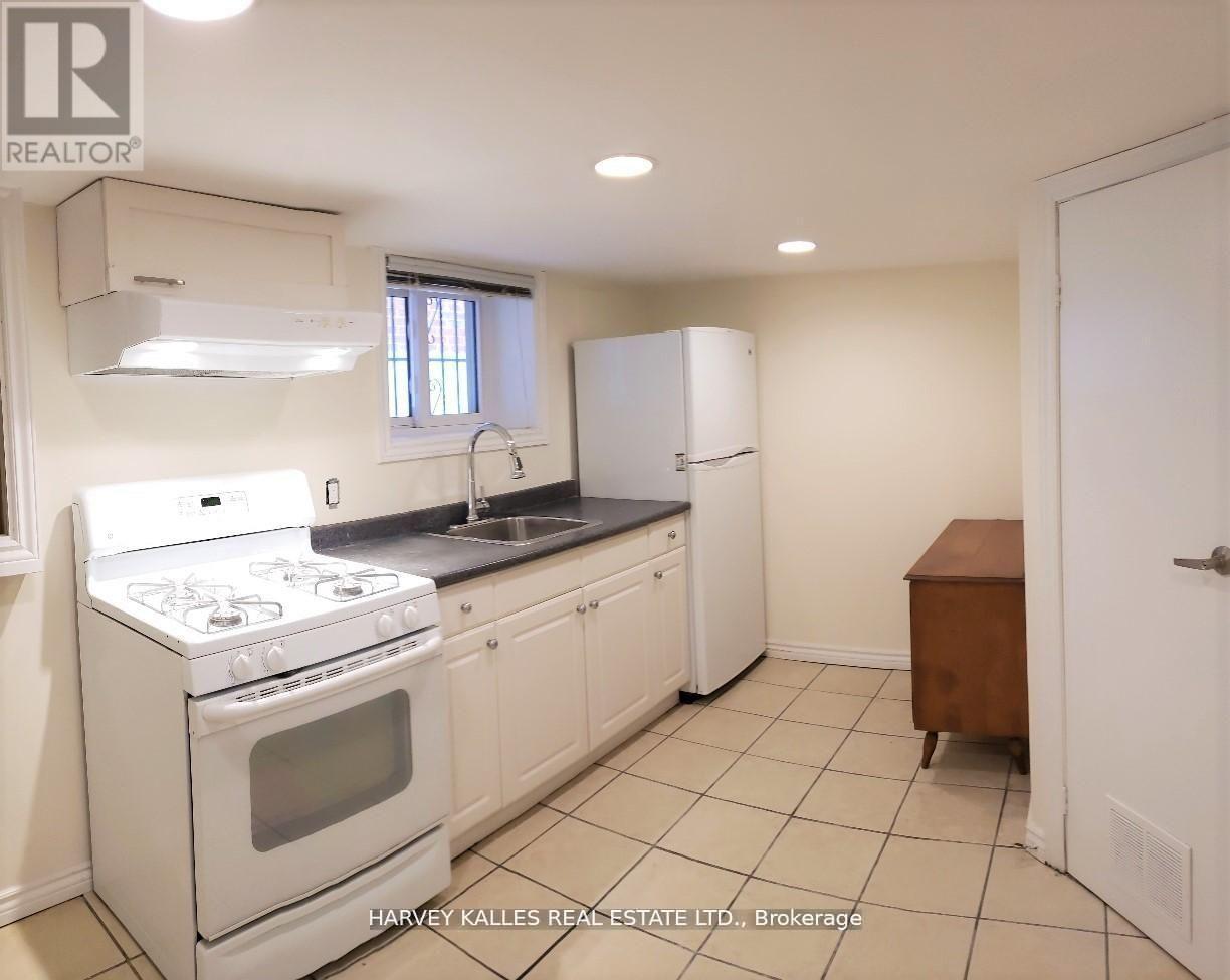 A white kitchen with a stove, sink, and cabinets.