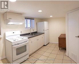 A white kitchen with a stove, sink, and cabinets.
