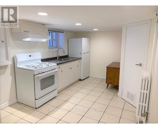 A white kitchen with a stove, sink, and cabinets.