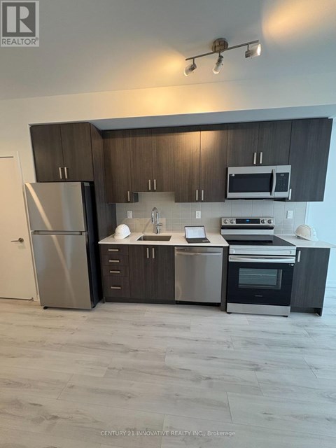 A modern kitchen with dark wood cabinets and stainless steel appliances.