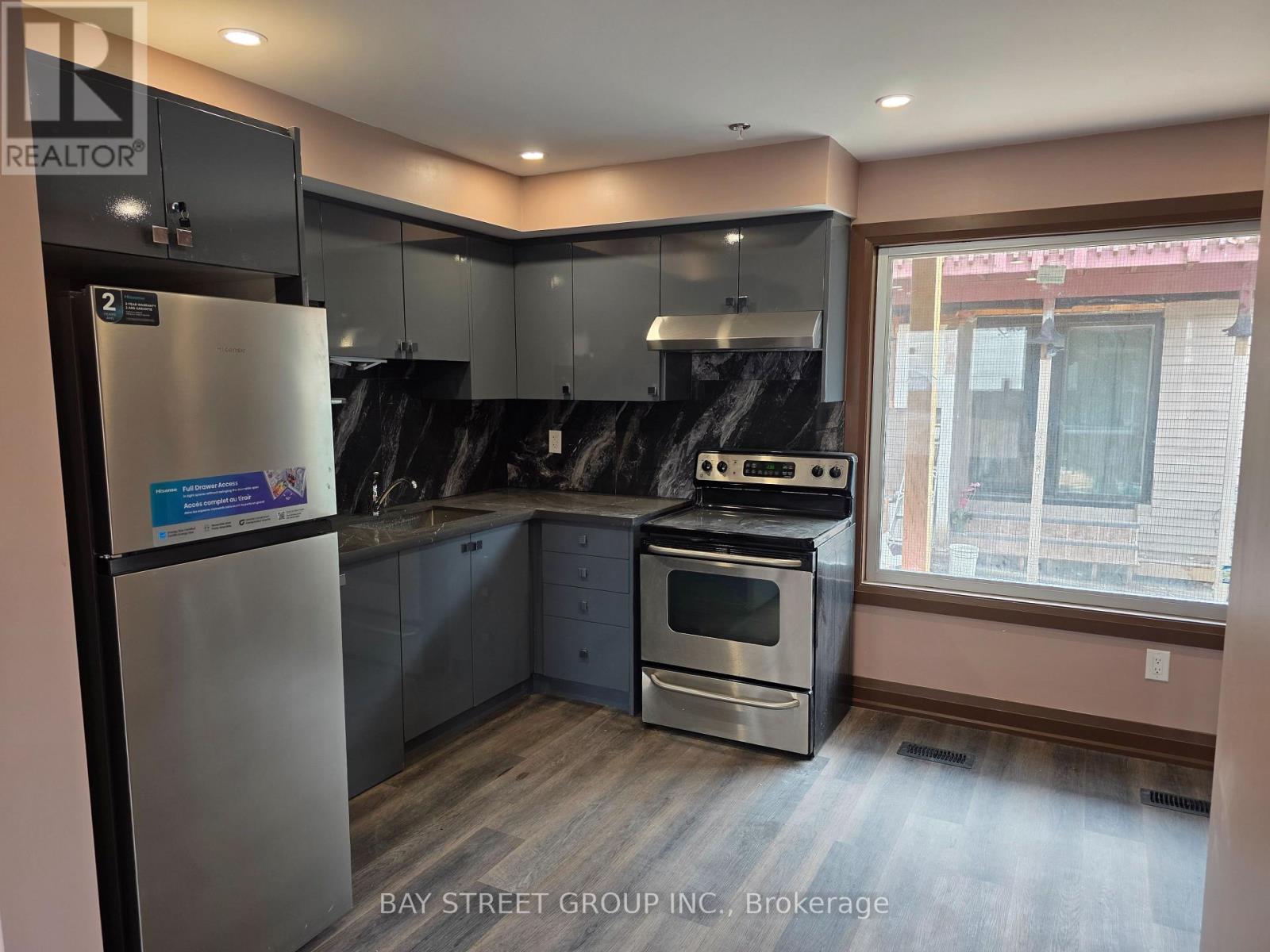 A kitchen with a refrigerator, oven, and sink.