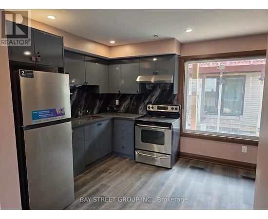 A kitchen with a refrigerator, oven, and sink.
