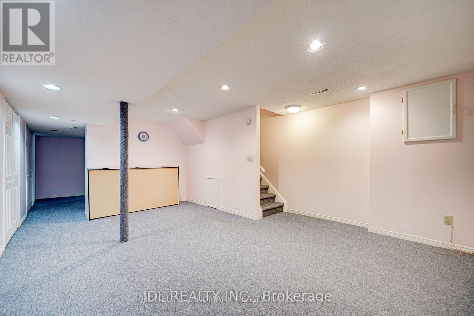 A spacious room with a staircase leading to the second floor.