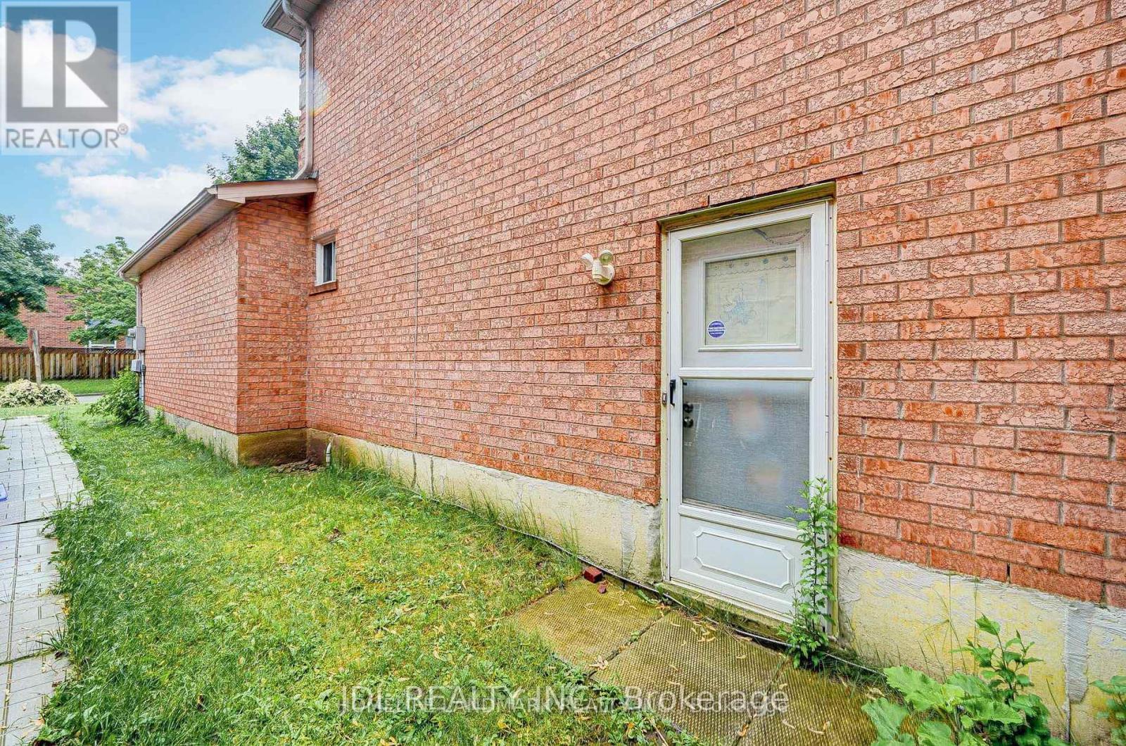 A red brick house with a white door and a window.
