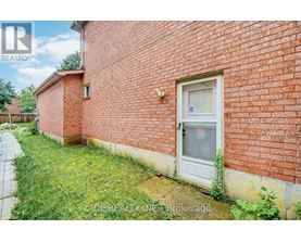 A red brick house with a white door and a window.