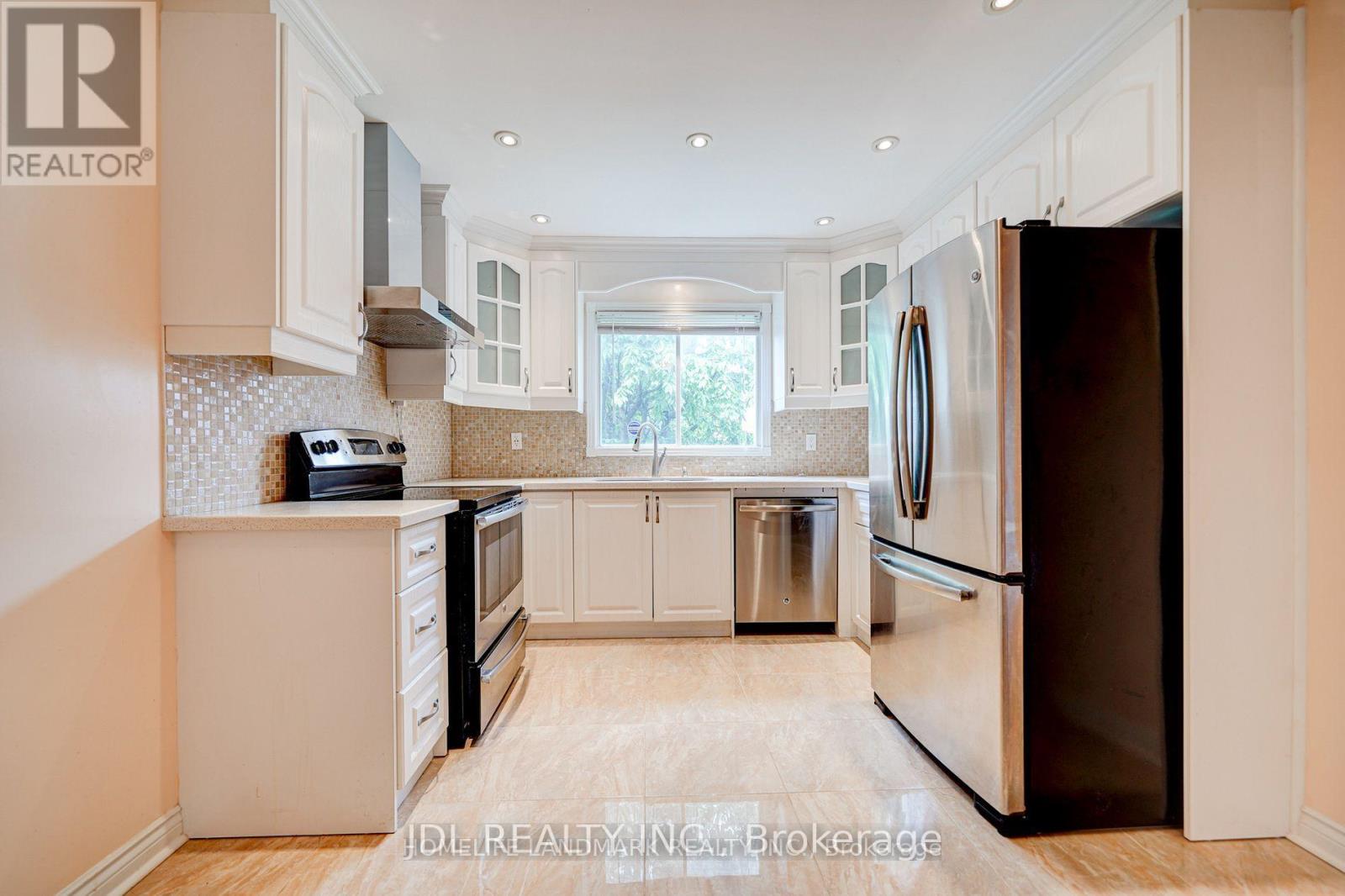 A kitchen with a black fridge and white cabinets.