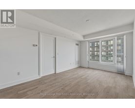 A spacious room with wooden flooring and a large window with a view of a cityscape.